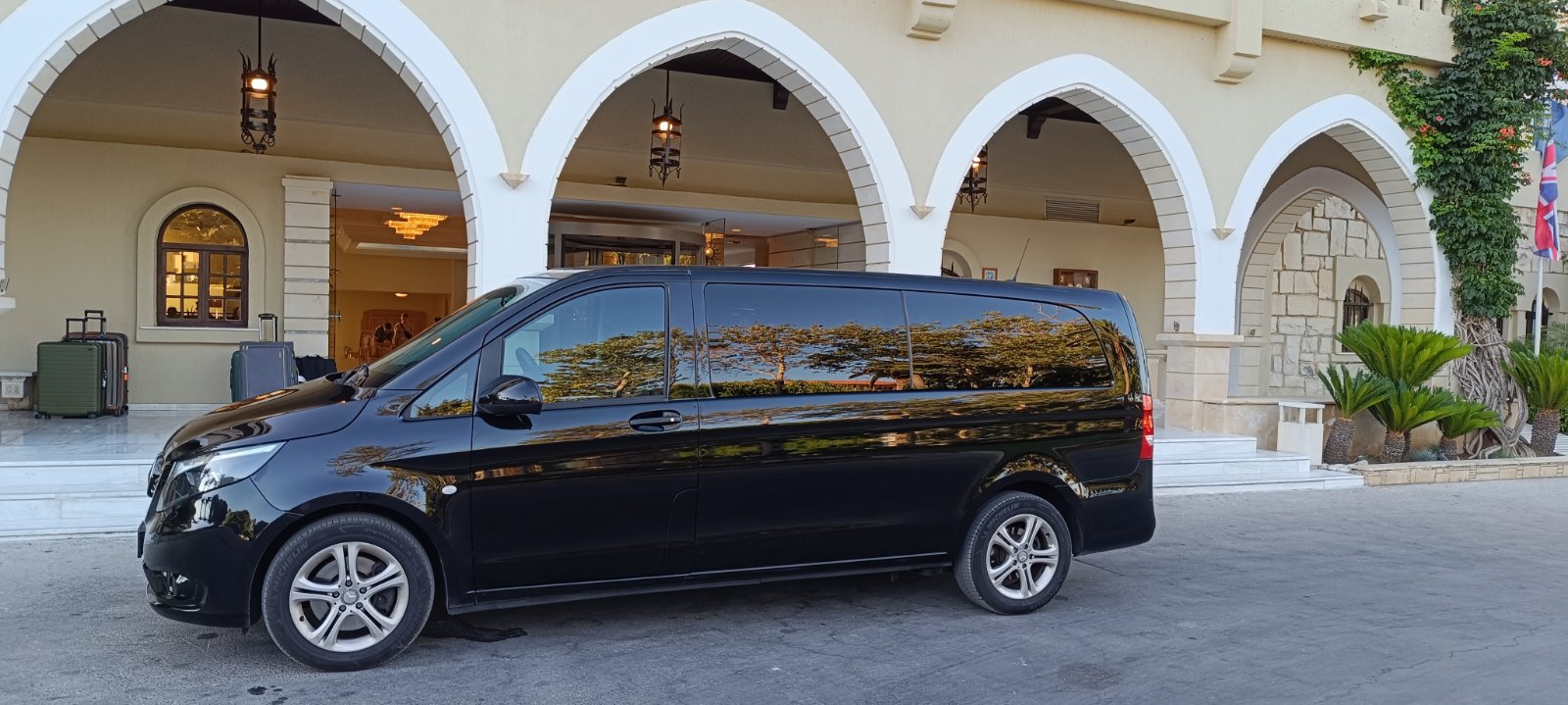 Black Mercedes V-Class waiting at a luxury hotel entrance in Crete